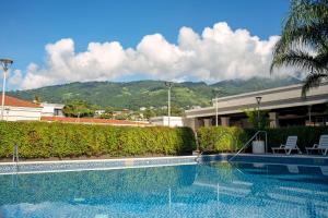 a swimming pool in front of a building with a mountain at Hilton San Salvador in San Salvador