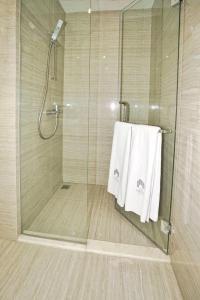 a shower with two white towels in a bathroom at The Cendana La Riz Mansion Pakuwon Mall in Surabaya