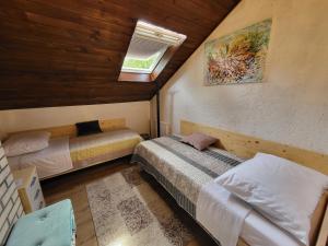 a attic bedroom with two beds and a window at Koča sredi gozda in Kanal +57 photos