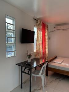 a room with a desk and a bed and a television at La Maria Traveller's Inn in Camparang
