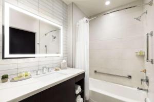 土桑Doubletree By Hilton Tucson Downtown Convention Center的带水槽、浴缸和镜子的浴室