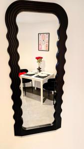 a dining room mirror with a white table and black chairs at Love nest 1er Étage in Abbeville
