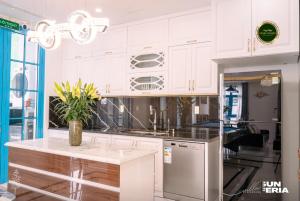 une cuisine avec des armoires blanches et un réfrigérateur en acier inoxydable dans l'établissement Chuỗi villa 7 Ngủ Sun feria 888 - bể bơi - BBQ -gần Bãi BIỂN BÃI CHÁY, à Hạ Long