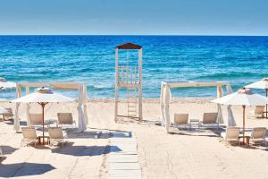 a group of chairs and umbrellas on the beach at Conrad Chia Laguna Sardinia in Chia