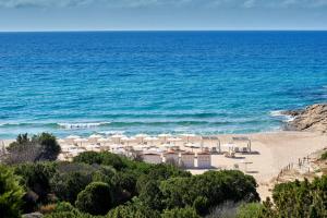 a beach with white umbrellas and the ocean at Conrad Chia Laguna Sardinia in Chia