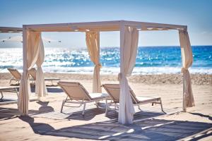 a group of chairs sitting under a gazebo on the beach at Conrad Chia Laguna Sardinia in Chia