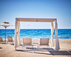 a wedding arch on a beach with chairs and the ocean at Conrad Chia Laguna Sardinia in Chia