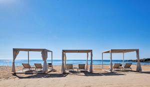 a group of chairs and a canopy on the beach at Conrad Chia Laguna Sardinia in Chia