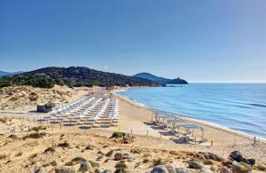 a beach with chairs and umbrellas on the sand at Conrad Chia Laguna Sardinia in Chia