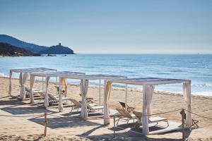 a row of tables and chairs on the beach at Conrad Chia Laguna Sardinia in Chia