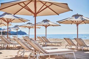 a group of chairs and umbrellas on a beach at Conrad Chia Laguna Sardinia in Chia