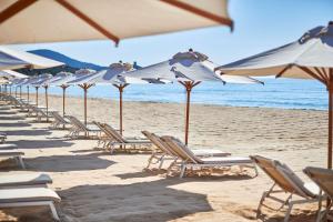 a row of chairs and umbrellas on a beach at Conrad Chia Laguna Sardinia in Chia