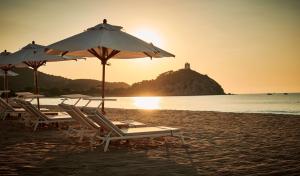a group of chairs and umbrellas on a beach at Conrad Chia Laguna Sardinia in Chia