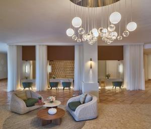 a living room with two couches and a chandelier at Conrad Chia Laguna Sardinia in Chia