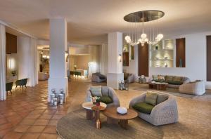 a living room with couches and tables and a chandelier at Conrad Chia Laguna Sardinia in Chia