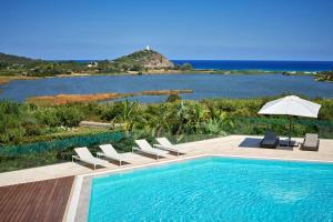 a swimming pool with chairs and an umbrella and the ocean at Conrad Chia Laguna Sardinia in Chia