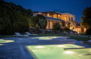 a building with a swimming pool in front of a building at Conrad Chia Laguna Sardinia in Chia