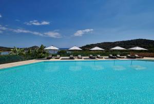 a swimming pool with chairs and umbrellas at Conrad Chia Laguna Sardinia in Chia