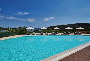 a swimming pool with chairs and umbrellas at Conrad Chia Laguna Sardinia in Chia