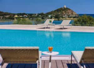 a drink on a table next to a swimming pool at Conrad Chia Laguna Sardinia in Chia
