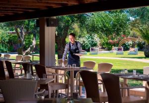 a man standing in front of tables in a restaurant at Conrad Chia Laguna Sardinia in Chia