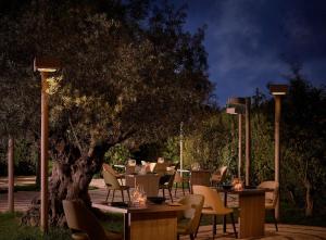 a restaurant with tables and chairs under a tree at night at Conrad Chia Laguna Sardinia in Chia