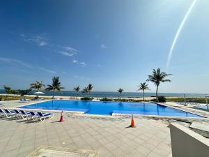 a swimming pool with chairs and palm trees and the ocean at Jebel paradise in Muscat