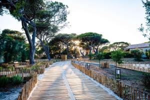une passerelle dans un parc avec une clôture et des arbres dans l'établissement Le Hameau Des Pesquiers Ecolodge & Spa, Curio Collection By Hilton, à Hyères
