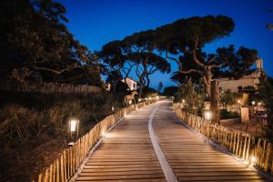une passerelle en bois éclairée la nuit dans l'établissement Le Hameau Des Pesquiers Ecolodge & Spa, Curio Collection By Hilton, à Hyères