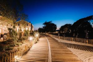 a wooden walkway with lights next to a building at Le Hameau Des Pesquiers Ecolodge & Spa, Curio Collection By Hilton in Hyères