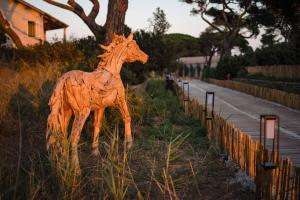 a wooden statue of a giraffe standing on the side of a road at Le Hameau Des Pesquiers Ecolodge & Spa, Curio Collection By Hilton in Hyères