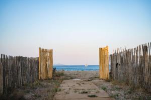 a fence on the beach next to the ocean at Le Hameau Des Pesquiers Ecolodge & Spa, Curio Collection By Hilton in Hyères