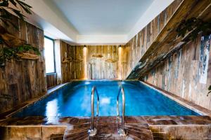 an indoor pool in a house with wooden walls and blue water at Le Hameau Des Pesquiers Ecolodge & Spa, Curio Collection By Hilton in Hyères