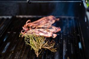 two pieces of meat cooking on a grill at Le Hameau Des Pesquiers Ecolodge & Spa, Curio Collection By Hilton in Hyères