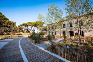 une passerelle en bois devant un bâtiment dans l'établissement Le Hameau Des Pesquiers Ecolodge & Spa, Curio Collection By Hilton, à Hyères