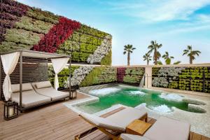 a patio with a pool and chairs and a wall with flowers at Conrad Rabat Arzana in Rabat