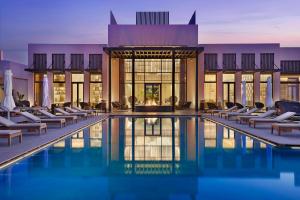 a hotel swimming pool with lounge chairs in front of a building at Conrad Rabat Arzana in Rabat