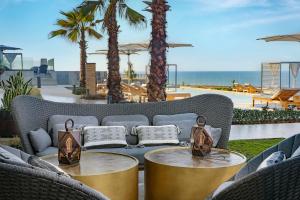 a patio with two tables and a couch with palm trees at Conrad Rabat Arzana in Rabat