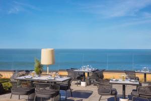 a patio with tables and chairs with the ocean in the background at Conrad Rabat Arzana in Rabat