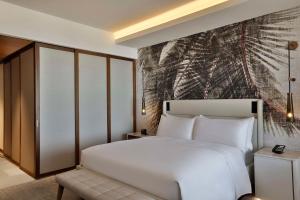 a bedroom with a white bed and a painting on the wall at Conrad Rabat Arzana in Rabat