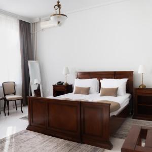 a bedroom with a large wooden bed with white pillows at Hotel Jardin in Belgrade