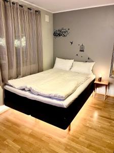 a bedroom with a bed with white sheets and a window at Panorama Storelva in Tromsø