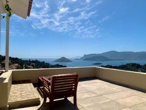 a wooden bench sitting on a balcony overlooking the ocean at Ersi's View in Porto Rafti
