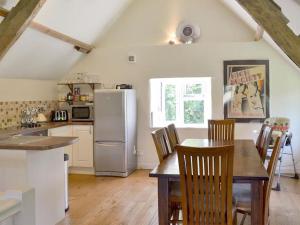 a kitchen with a table with chairs and a refrigerator at Beautiful Dartmoor cottage overlooking vineyard in Bridford