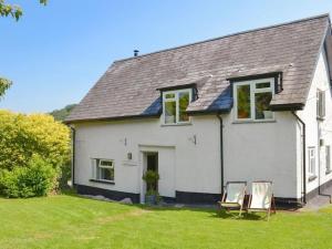 a white house with two chairs in the yard at Beautiful Dartmoor cottage overlooking vineyard in Bridford