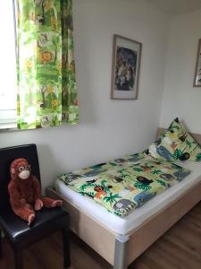 ein Bett mit ausgestopftem Affen, der auf einem Stuhl sitzt in der Unterkunft Ferienwohnung Nähe Legoland Günzburg 86 qm mit Balkon in Burtenbach