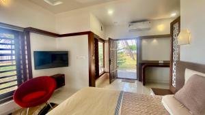 a bedroom with a bed and a red chair at Willo stays beach cottage in Kannur