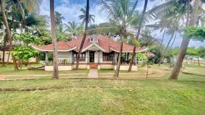 a small house with palm trees in a yard at Willo stays beach cottage in Kannur