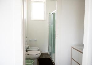 a white bathroom with a toilet and a window at Rocca dei tramonti in Punta Braccetto