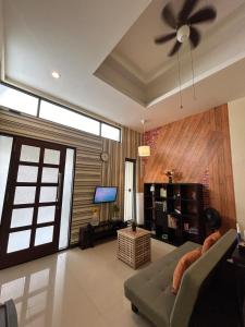 a living room with a couch and a ceiling fan at Dea's House Homestay in Blimbing